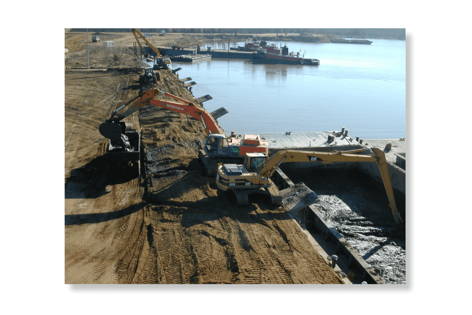 Excavator working a barge of dredged material at the Weanack dock