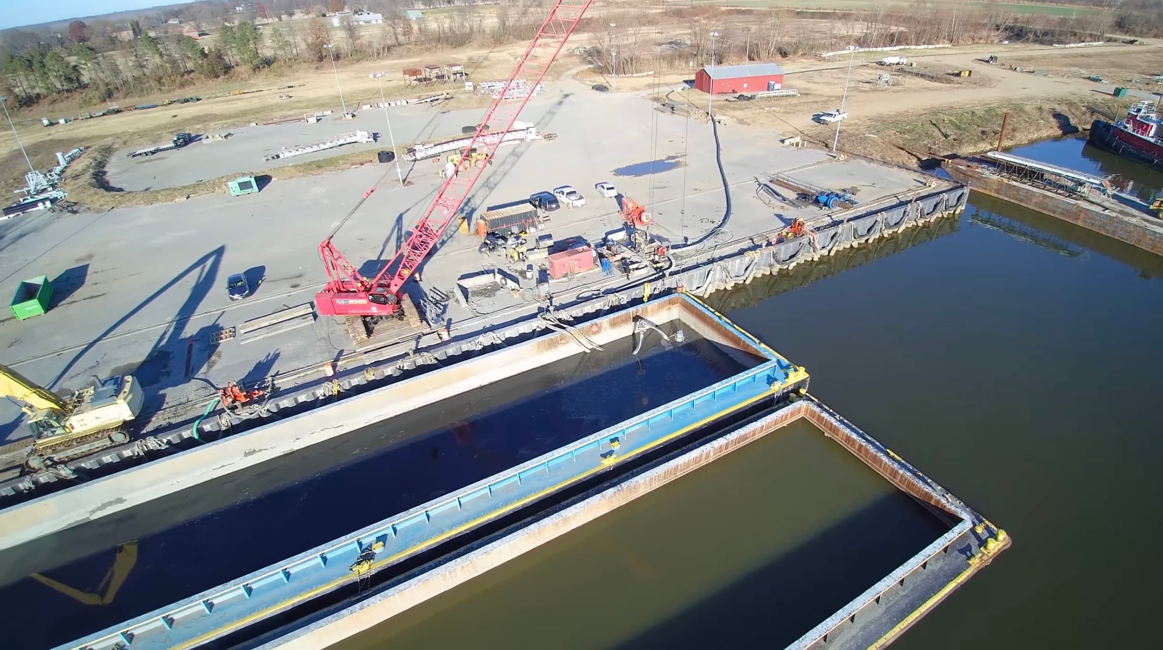 Aerial view of a crane pumping dredged material from a barge into a containment basin at the Weanack dock